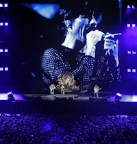 the rolling stones on stage in front of a large screen