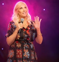 a woman in a floral dress is speaking into a microphone