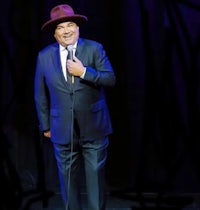 a man in a suit and hat is holding a microphone