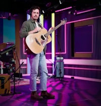 a man playing an acoustic guitar on a stage