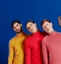 three men in colorful sweaters posing in front of a blue background